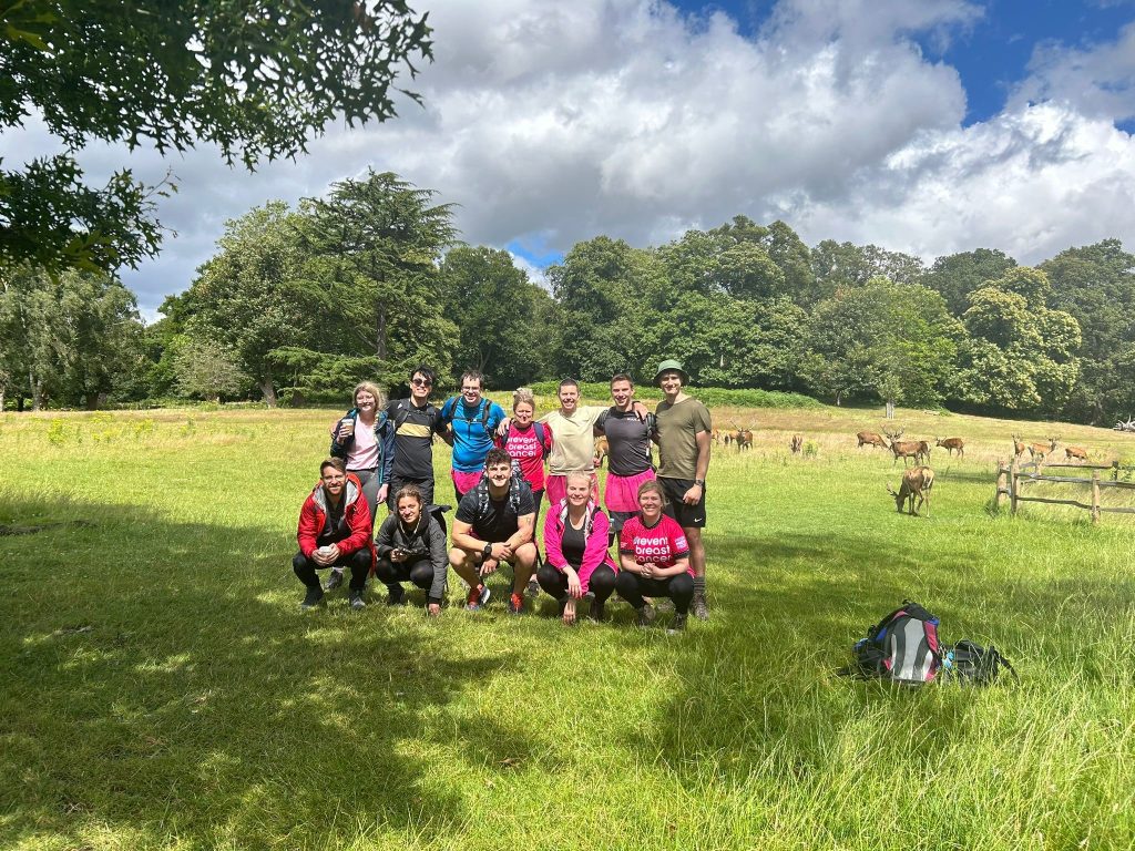 Photo of the team, in a field, with deer behind